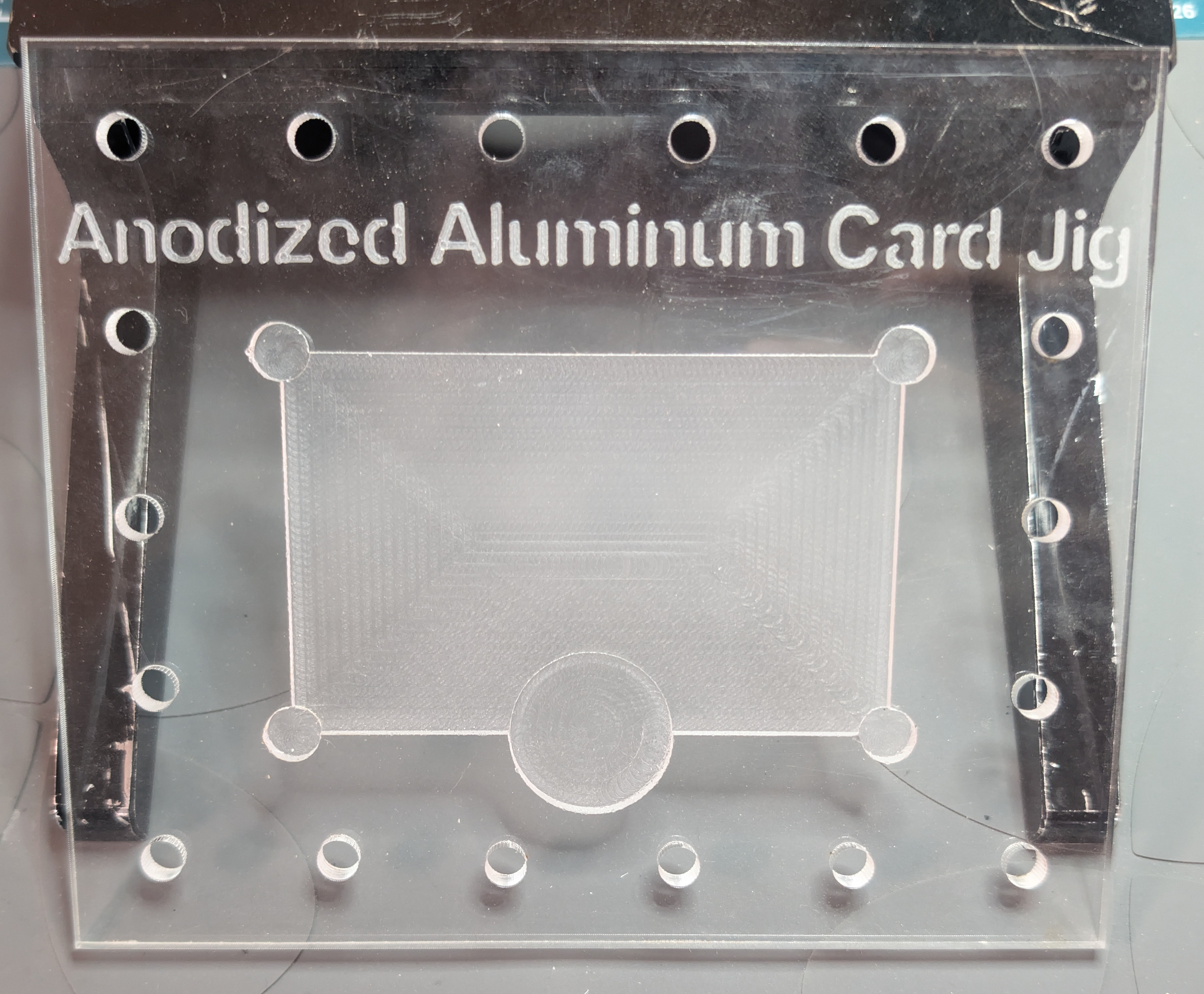 Acrylic jig used to position the card for laser cutting, with cutout in middle and positioning holes for repeatability